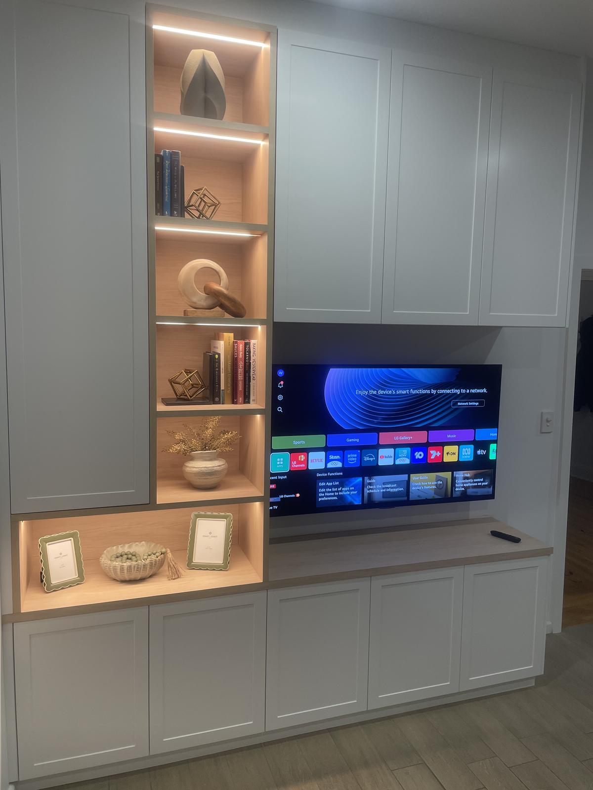 Home entertainment unit with wall-mounted TV and LED shelf lighting
